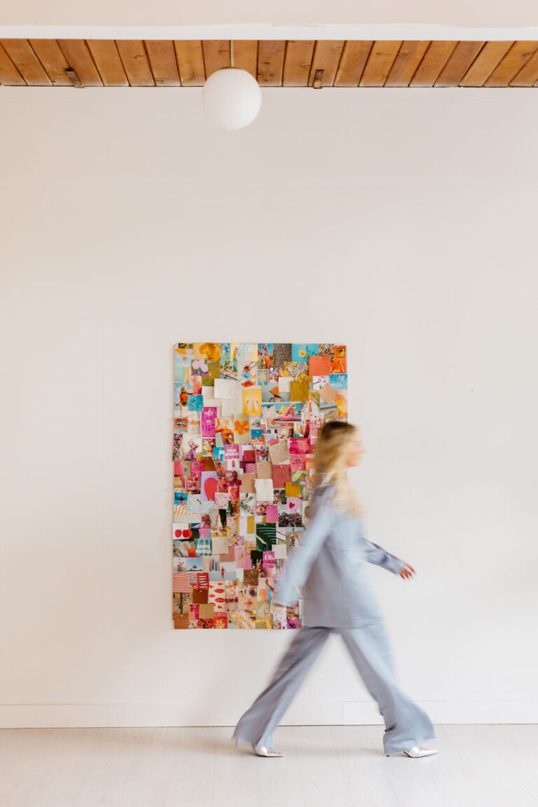 A woman walking in a blurry pace in front of a mood board in a studio