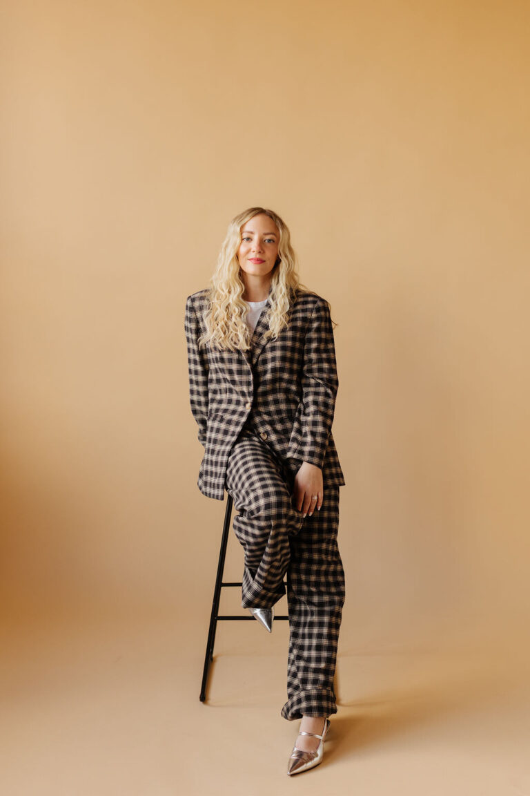 woman in power suit posing on a stool in a studio