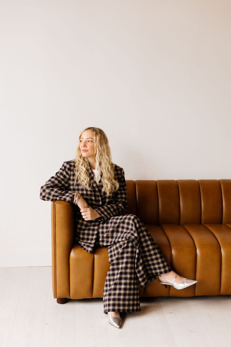 A portrait of a woman sitting on a leather couch in a studio with natural light photography