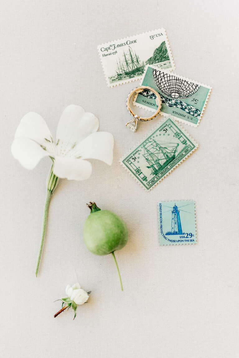 Flat lay of wedding decor including wedding ring, vintage stamps, florals, photographed by a los angeles wedding photographer