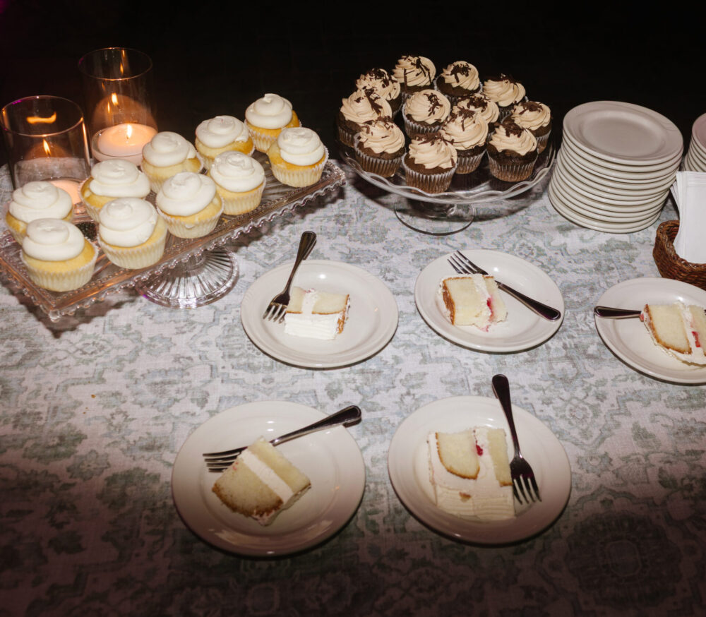 Wedding dessert spread with cake, cupcakes, and beautiful linens taken with flash photography
