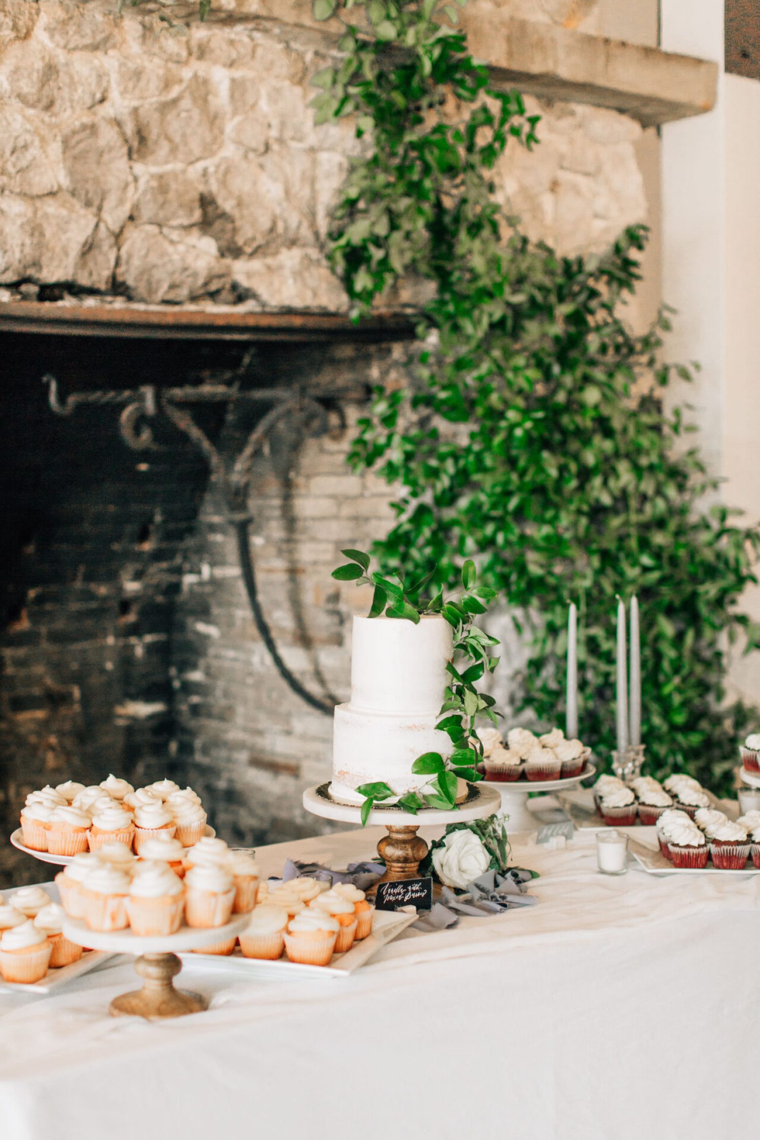 A wedding dessert display with a cake and garland draped on a fireplace, photographed by a los angeles wedding photographer