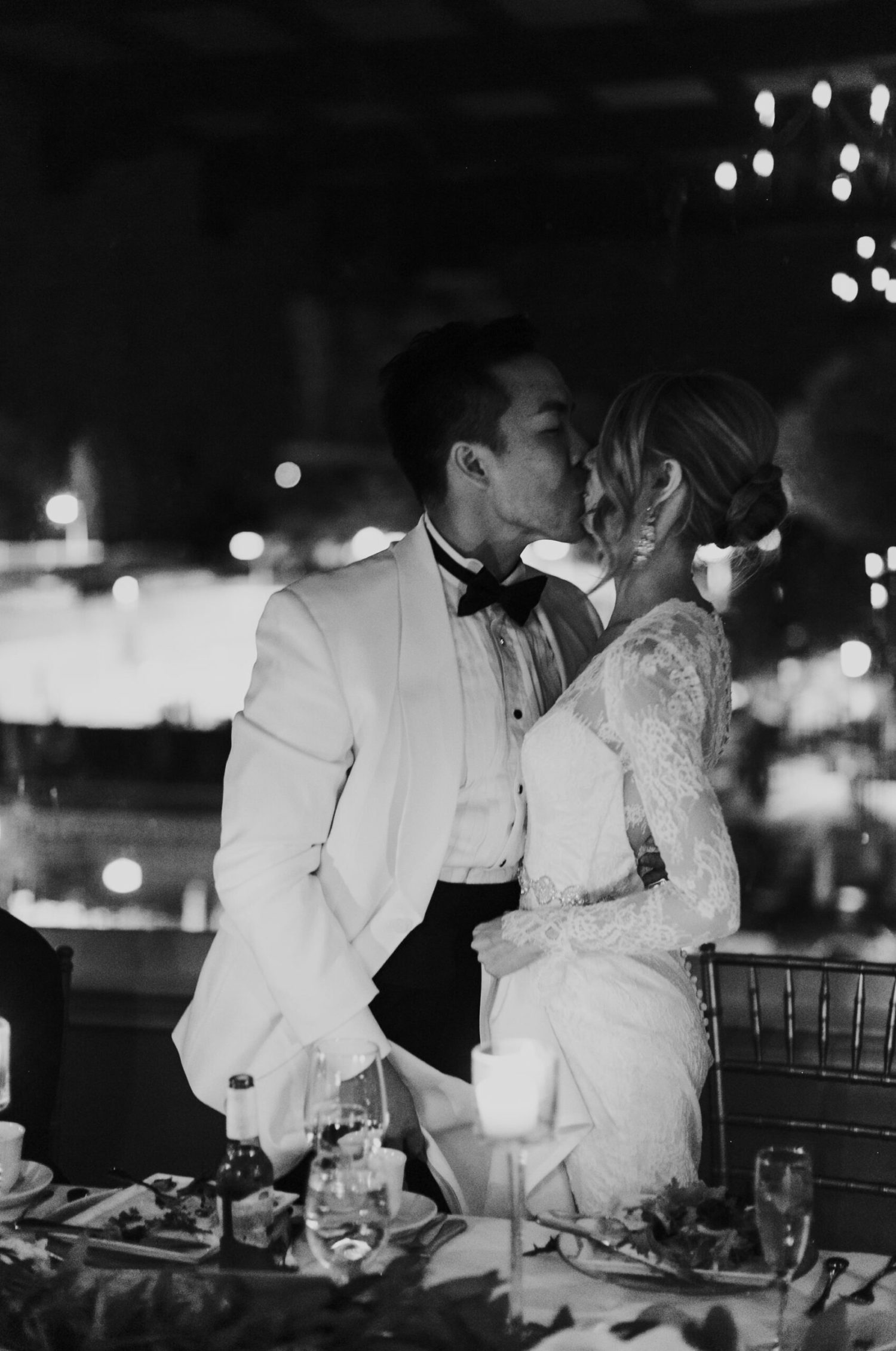 a black and white image of a bride and groom kissing at their wedding reception